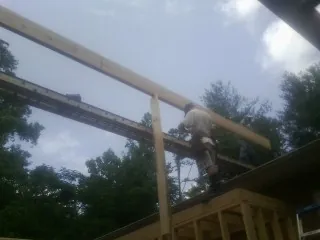 Carpenter setting a ridge beam over a new addition frame — Ice Dam Removal by Roofing Brothers in Saint Marys City