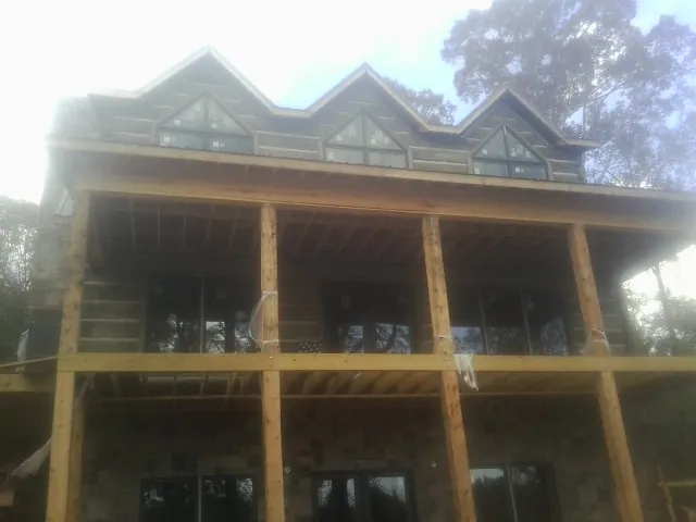 Dormers and porch framing on a large log home under construction — Roof Coating work by our crew in Saint Marys City