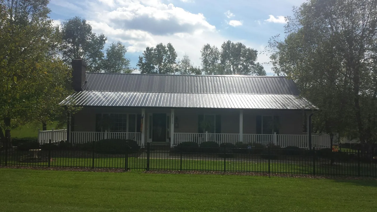 Gray metal roof on a brick ranch with a full width front porch — Gutter Guard Installation work by our crew in Saint Marys City