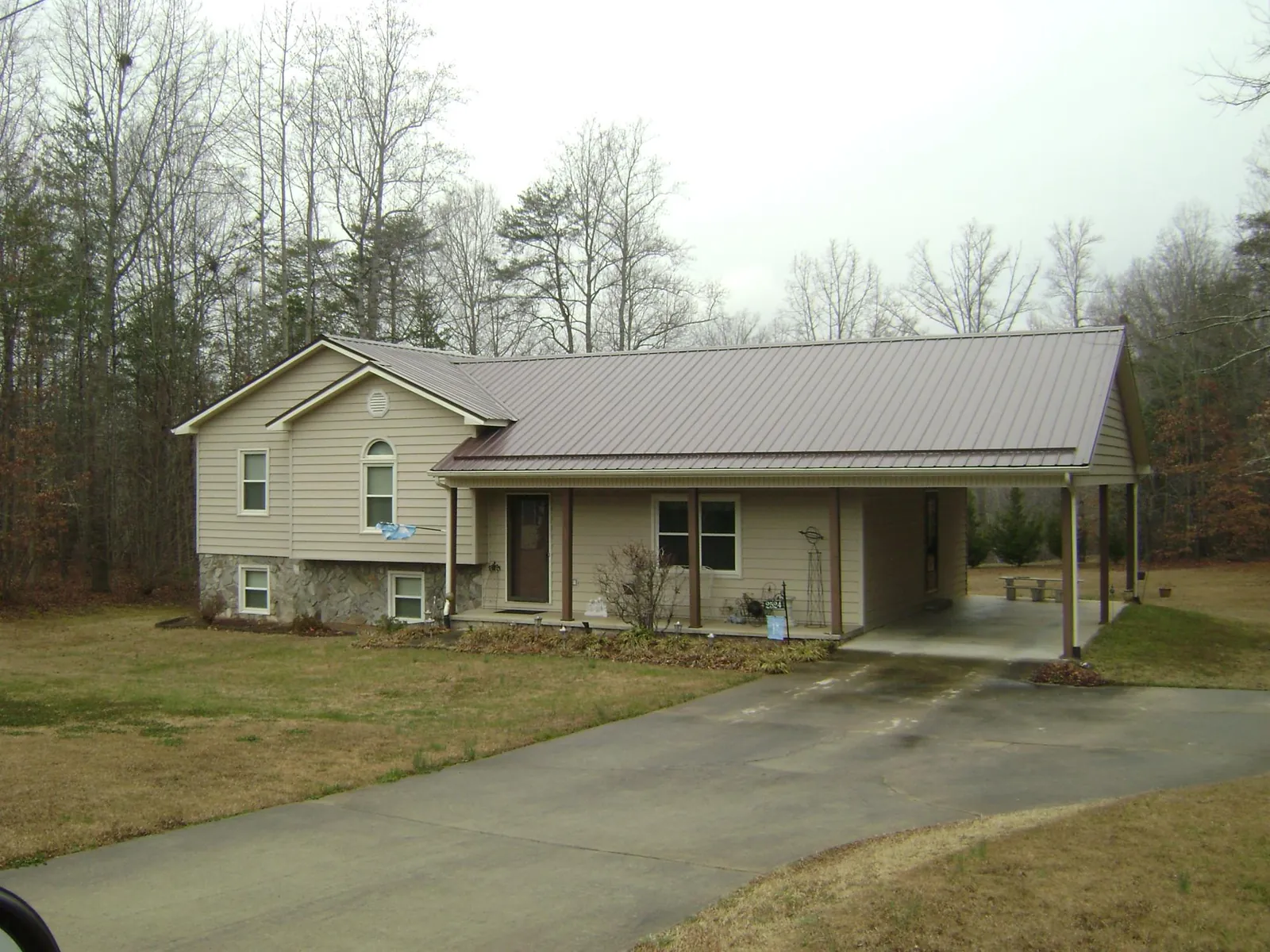 Brown metal roof on a tan split level home with an attached carport in Saint Marys City