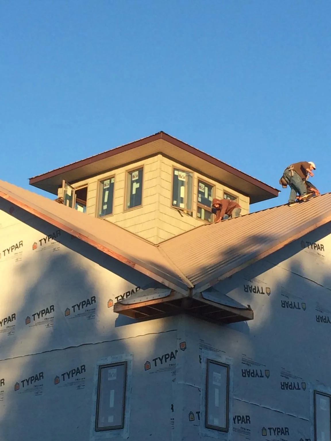 Roofers working around a rooftop cupola on a new metal roof at sunset — Roof Waterproofing in Saint Marys City by Roofing Brothers